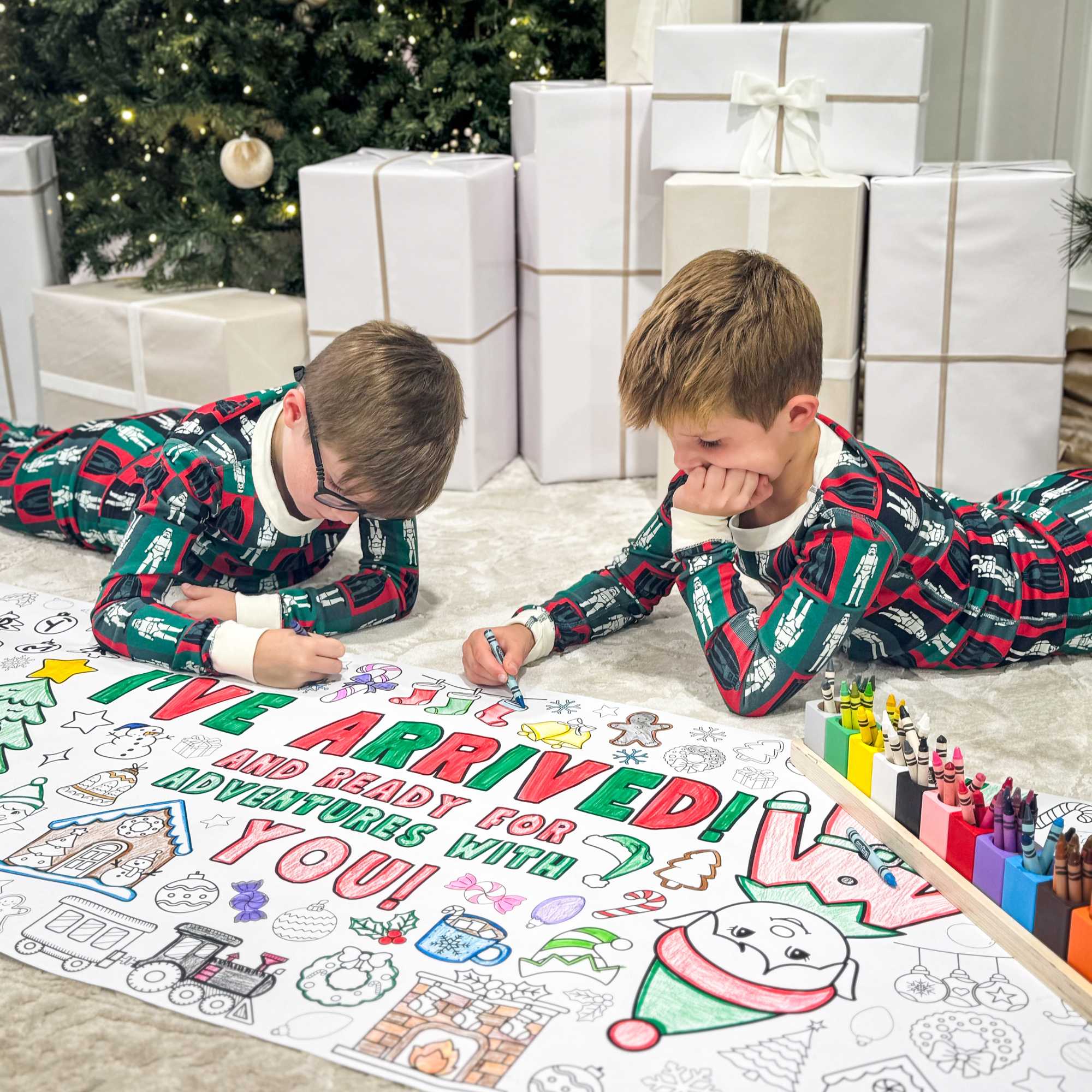 Complement your Elf Kit 2025 with an Elf Arrival Giant Coloring Banner so your elf doesn’t just sit on the shelf. This Elf Arrival Banner is full of magic,  themes to make your elf's arrival grand adventure.  Check out our shop for a fun elfin adventures while waiting around for Santa in December! Coloring banner with Christmas-themed elements and text, featuring two children in pajamas coloring a large sheet of paper with Christmas-themed activities, surrounded by Christmas decorations.