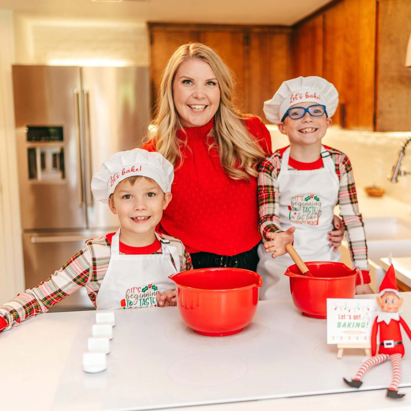 elf prop, baking, kitching, kids apron and chef hat, Woman and two children in a kitchen wearing chef hats and aprons, with baking equipment.